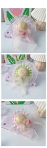 Detail of pet straw hat with lace edges, silk roses, and organza bows in pink and green