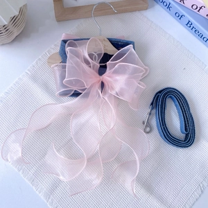 Macro detail of denim pet harness with large pink organza bow and matching lead