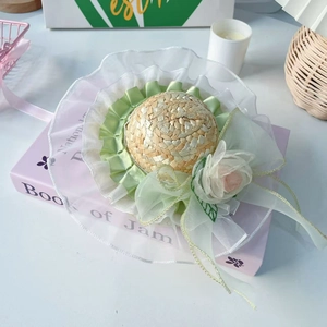 Detail of pet straw hat with green lace, white mesh trim and a pink fabric rose