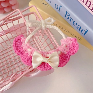 Detailed close-up of pink crochet pet scarf with white satin bow on mini shopping basket