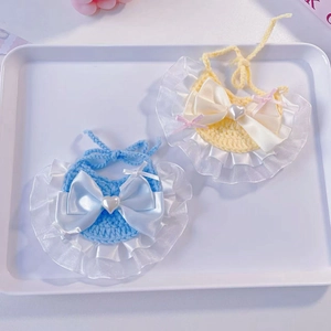 Dettaglio bavaglini per animali fatti a maglia con fiocchi di raso e perle a cuore blu e gialli