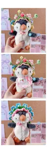 Detail of penguin plush toy wearing various handmade crochet flower hats and peach bib