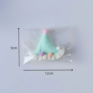 Knitted pet party hat in mint green with colorful pompoms and size markings