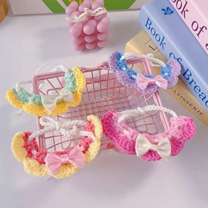 Detail of four handmade crochet pet bibs with lace edges and satin bows in diverse colors