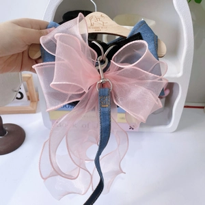 Close-up of blue denim pet harness set with a large pink organza bow and metal buckles