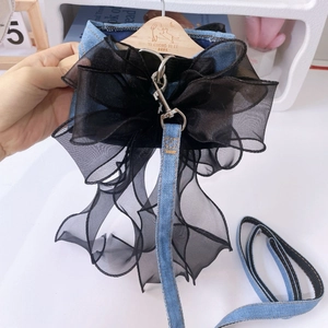 Detailed texture of denim pet harness with black layered mesh bow and silver buckle