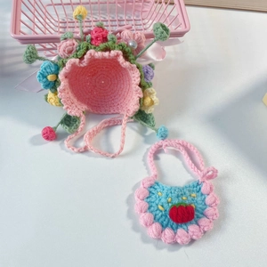 Handmade crochet pet hat with pink flowers and a blue bib featuring strawberry embroidery