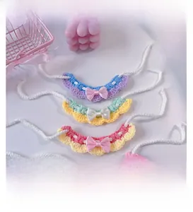 Close-up of four handmade crochet pet bibs in macaron colors with satin bows and ties