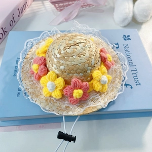 Close-up of hand-woven pet straw hat with lace brim and colorful knitted flowers