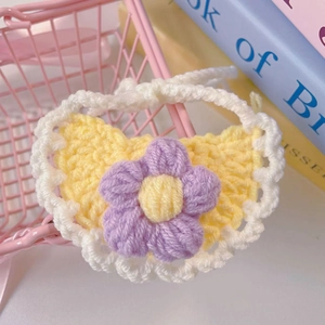 Macro detail of hand-knitted pet bib with yellow heart and purple floral embellishment