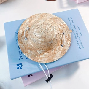Close-up of mini pet straw hat with adjustable elastic strap and buckle detail