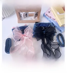 Close-up of denim pet harness set with large organza bow and matching leash on table