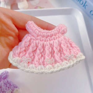 Detail of a pink hand-crocheted doll dress with white bows and pearl accents for 15cm dolls