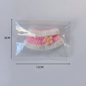 Detail of pink and white knit doll dress with 3D flower decoration in package