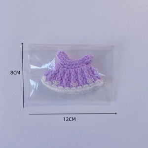 Handmade purple crochet doll dress with white trim and bow accents in packaging