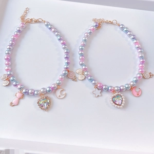 Detail of gradient pearl pet necklace with heart and cat pendants on white tray