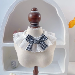 Detail of pet lace collar with a black and white gingham bow on a fabric mannequin