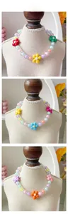 Détail de colliers colorés en perles macaron pour animaux avec breloques fleurs