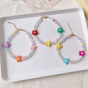 Détail de colliers en perles macaron pour animaux avec pendentifs fleurs et fermoirs dorés