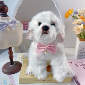 Detailed close-up of a pink lace bow collar with a pearl pendant on a white toy dog