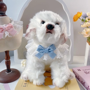 Detail of white plush puppy doll wearing a lace pet collar with a blue checkered bow tie