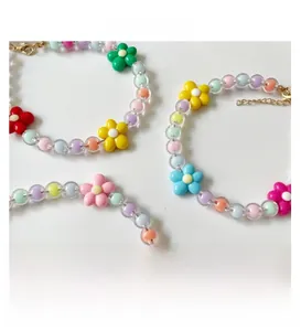 Détail de colliers pour animaux avec perles macaron, breloques fleurs et fermoir réglable
