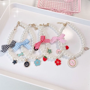 Detailed close-up of pearl pet necklaces with colorful plaid bows and enamel charms