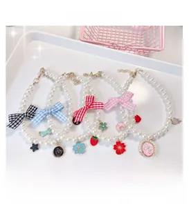 Detail of diverse handmade pearl pet collars with gingham bows and colorful alloy pendants