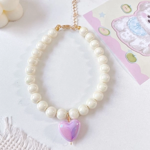 Detail of colorful pet necklace with white pearls and iridescent purple heart pendant