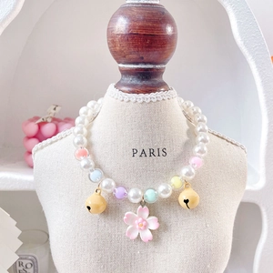 Detailed close-up of a pearl pet necklace featuring a pink flower pendant and small bells