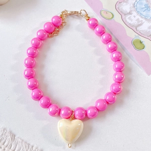 Detailed shot of pink beaded pet necklace with iridescent heart pendant and gold clasp