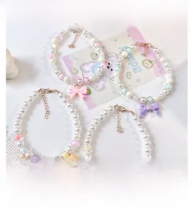 Detail of four pet pearl collars with pink bows, bells, and floral charms for cats