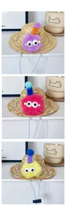 Detail of pet straw hat with colorful plush monster decor and adjustable elastic chin strap