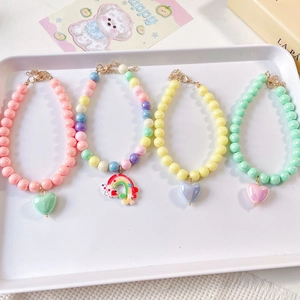 Detail of colorful beaded pet collars with heart and rainbow charms on a white tray