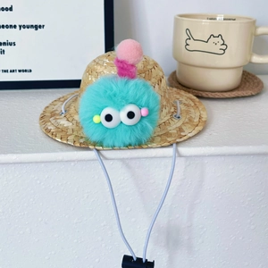 Detail of pet straw hat with blue pom pom monster and adjustable elastic chin strap