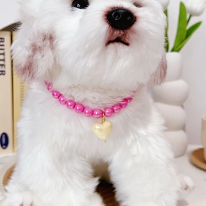 Pink pearl pet necklace with yellow heart pendant worn by a small white dog