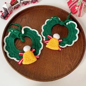 Green knit pet Christmas collar with bell decoration and white trim on wood tray