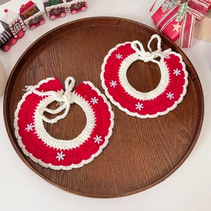 Detail of two red and white crochet pet collars with snowflake patterns on a tray