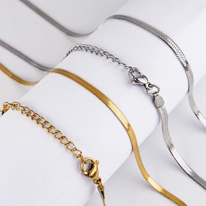 Detailed macro view of flat gold and silver snake chains with lobster clasps and extenders