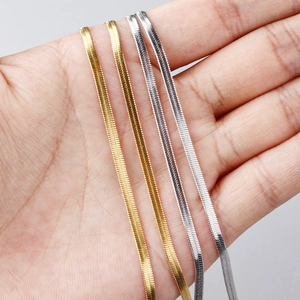 Flat stainless steel snake bone chains in gold and silver held in hand for jewelry DIY