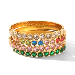 Gros plan de bracelets en acier inoxydable doré avec des zircons en forme de cœur.