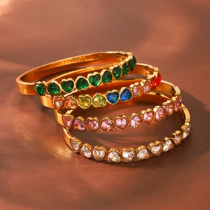 Gros plan de quatre bracelets en acier doré avec zircons colorés en forme de cœur