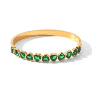 Détail d'un bracelet jonc en acier doré orné de zircons verts en forme de cœur