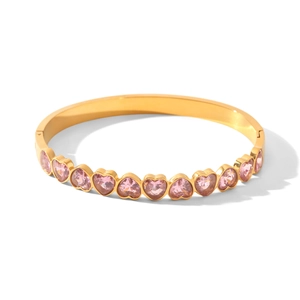 Détail d'un jonc doré en acier inoxydable orné de zircons en forme de cœur rose