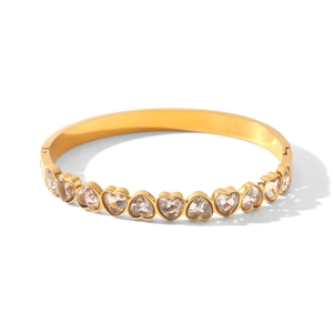 Vue détaillée des sertis en zircon en forme de cœur sur un bracelet jonc en acier doré.