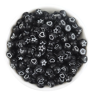 Macro detail of black acrylic beads with white star and heart patterns for DIY crafts