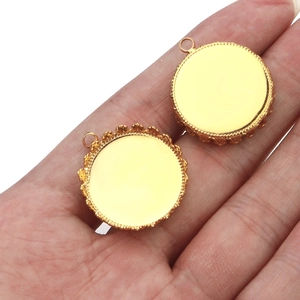 Macro detail of two bright gold crown-edged pendant trays held for size reference
