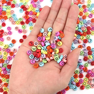 Flat round acrylic beads with star and heart patterns shown on a palm for DIY jewelry