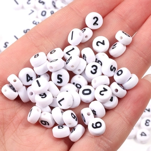 Macro view of 7mm white acrylic beads with black numbers for DIY jewelry making