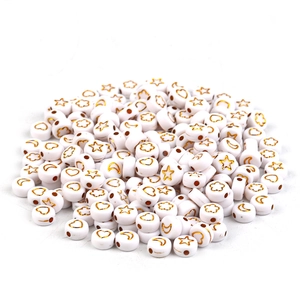 Macro shot of white acrylic flat beads with golden star and heart patterns for DIY crafts